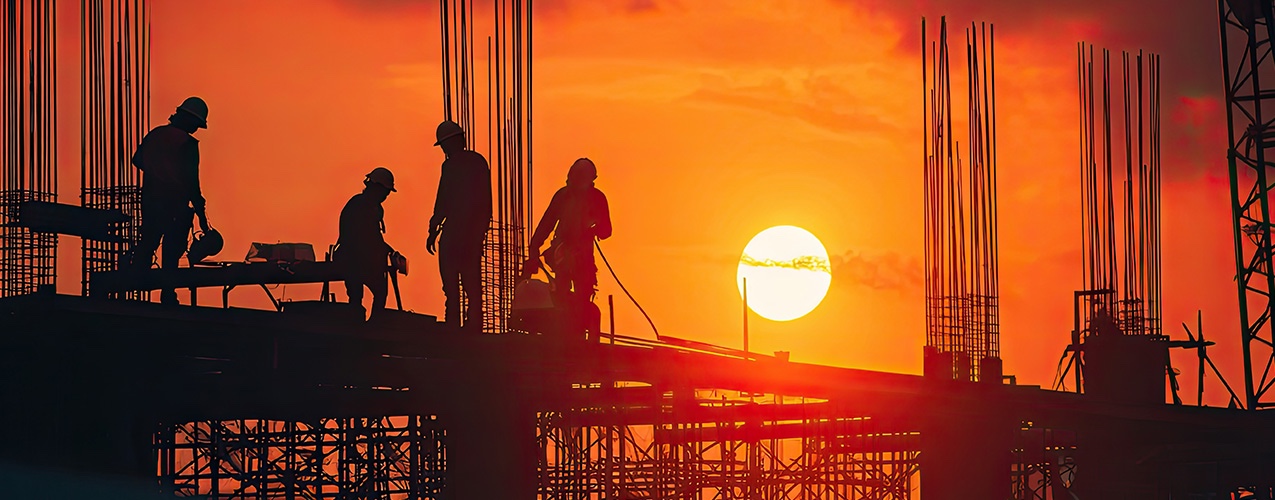 eim construction workers on a building frame at sunset, with steel reinforcement