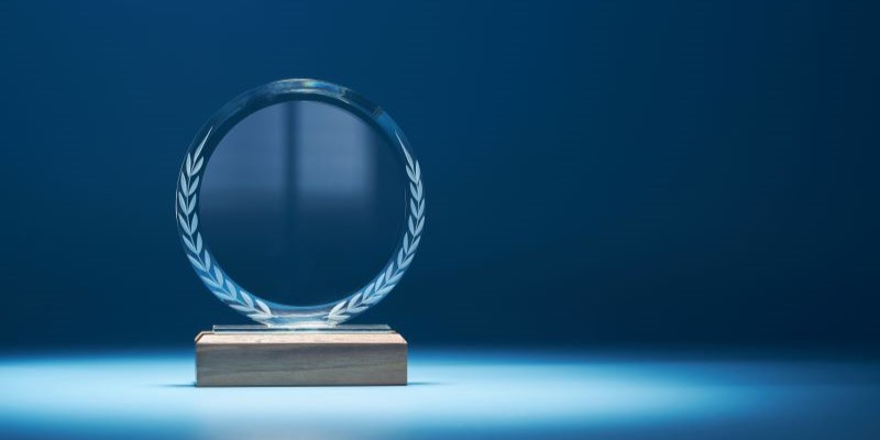 Glass trophy with wooden bottom against a blue background