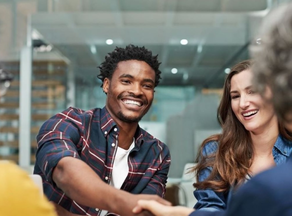 Idox Lilie Sexual Health Software Idox Lilie EPR software users smiling and shaking hands during a meeting, representing positive customer experience.