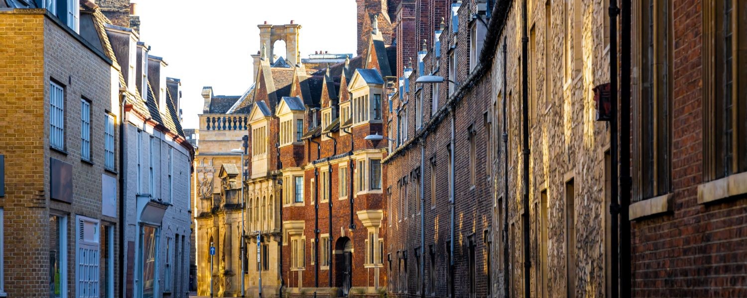 Sunny day view of Cambridge, England, showing historic university buildings and the River Cam with trees and riverside scenery